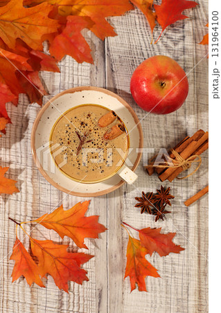 Indian masala chai with milk, ginger, anise, and cinnamon on an old wooden table with fallen autumn leaves. A traditional seasonal drink with spices, a cafe advertising card, a restaurant menu. Indian masala chai with milk, ginger, anise, and cinnamon on an old wooden table with fallen autumn leaves. A traditional seasonal drink with spices, a cafe advertising card, a restaurant menu. 131964100