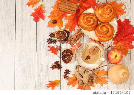 Cinnamon rolls with hot autumn drink, coffee glace and autumn fallen leaves, star anise, ginger and cinnamon on marble table, banner for display, autumn greeting concept, mockup for menu. Cinnamon rolls with hot autumn drink, coffee glace and autumn fallen leaves, star anise, ginger and cinnamon on marble table, banner for display, autumn greeting concept, mockup for menu. 131964103
