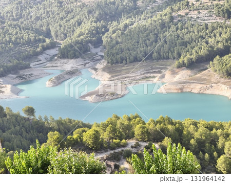 An aerial view captures a vibrant turquoise lake surrounded by lush greenery and landscapes 131964142