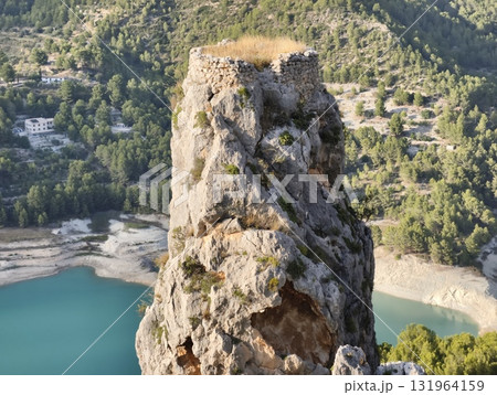 A scenic rock formation with ancient ruins, majestically overlooking a serene lake A scenic rock formation with ancient ruins, majestically overlooking a serene lake 131964159