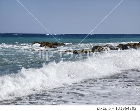 Experience the serene ocean waves gracefully crashing on the beautiful rocky shoreline 131964202