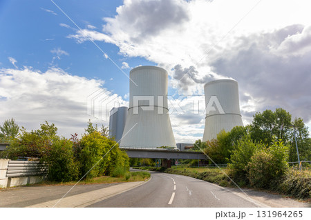 Massive cooling tower power plant Saxony  Germany releasing steam  cloudy sky. Industrial complex surrounded by fields illustrates modern energy generation, infrastructure environmental technology 131964265