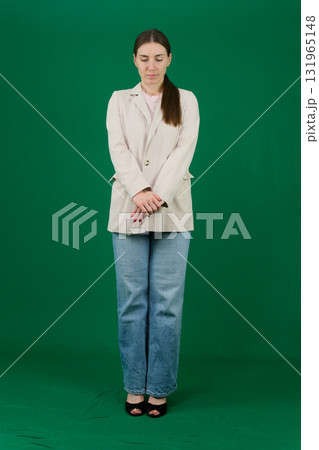 Set of photos of young European woman in light blazer and blue jeans showing various emotions gestures and expressions on green chroma key background with copy space for advertising and social media 131965148