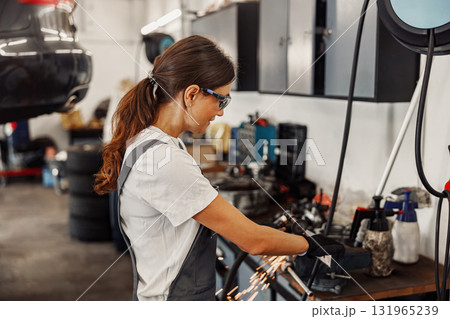 A Skilled Female Mechanic Engaged in Work at an Auto Repair Shop for Vehicles and Cars 131965239