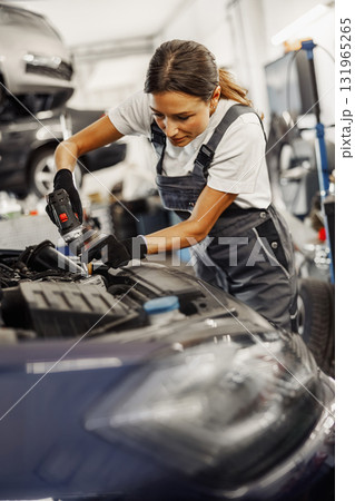 A highly skilled mechanic diligently working on a complex car engine in the workshop environment 131965265