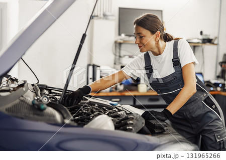 A Skilled Female Mechanic is Currently Engaged in Repairing a Car Engine in a Workshop Setting 131965266