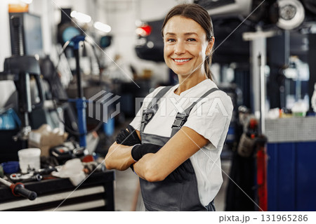 A Smiling Female Mechanic Working Diligently in a Busy Automotive Workshop Environment A Smiling Female Mechanic Working Diligently in a Busy Automotive Workshop Environment 131965286