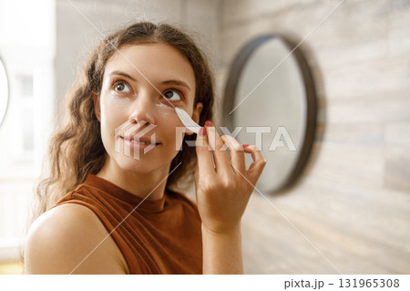 A Woman Applying Skincare Products In A Modern Stylish Bathroom Setting That Exudes Elegance A Woman Applying Skincare Products In A Modern Stylish Bathroom Setting That Exudes Elegance 131965308