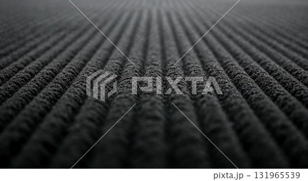A macro perspective reveals textured dark gray parallel ridges receding into the distance, highlighted by subtle light, creating an abstract patterned surface. 131965539