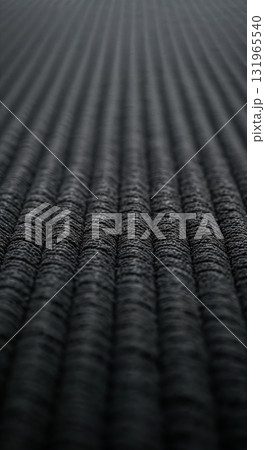 A detailed macro perspective reveals a dark gray textured surface featuring numerous parallel undulating ridges that recede into a soft focus. A detailed macro perspective reveals a dark gray textured surface featuring numerous parallel undulating ridges that recede into a soft focus. 131965540
