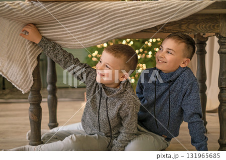 Boys hide under the Christmas table from their parents, waiting for Christmas to come. 131965685