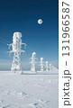 A row of snow-covered power line towers extends across a vast frozen landscape under a clear blue sky with a prominent full moon. 131966587