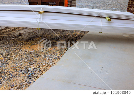 Stacked building materials rest at construction site on gravel surface under works day Stacked building materials rest at construction site on gravel surface under works day 131968840