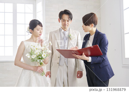 悩みながら打ち合わせする結婚式の司会者と新郎新婦 悩みながら打ち合わせする結婚式の司会者と新郎新婦 131968879