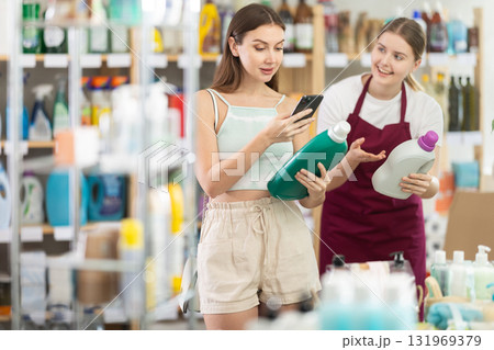 Seller offers woman detergent while customer scans barcode on phone Seller offers woman detergent while customer scans barcode on phone 131969379