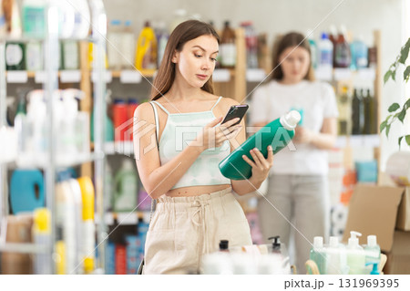 Woman scanning a package of detergent on her phone Woman scanning a package of detergent on her phone 131969395
