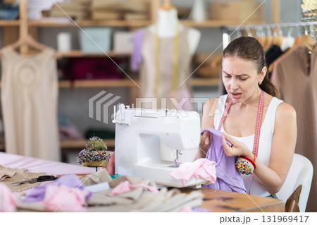 Girl injured hand while working at sewing machine. 131969417