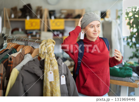 Teenage girl tries on hat in clothing store 131969446