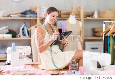 Young female dressmaker drawing on tablet in sewing workshop Young female dressmaker drawing on tablet in sewing workshop 131969509