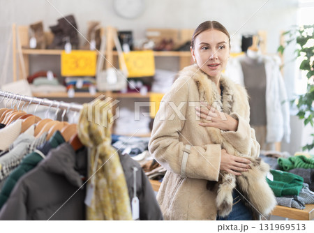 Adult woman trying on fur coat in store 131969513