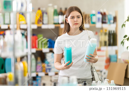 Young woman choosing shampoo or shower gel in store 131969515