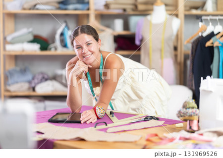 Female tailor create sketch of dress in tablet 131969526