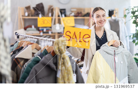 Adult woman holding sale sign in clothing store Adult woman holding sale sign in clothing store 131969537
