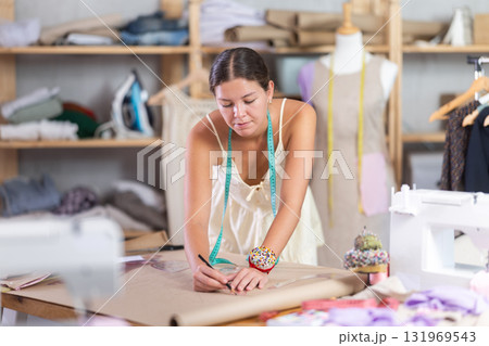 Using curve ruler, woman tailor draws dress diagram scheme on paper Using curve ruler, woman tailor draws dress diagram scheme on paper 131969543