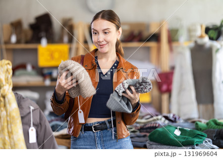 Focused european young woman choose hat on Black Friday sale of winter clothing collection in clothing store 131969604