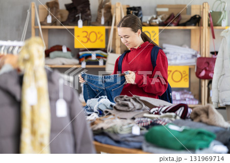 Teenage girl choosing jeans in clothing store Teenage girl choosing jeans in clothing store 131969714