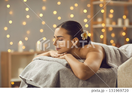 Beautiful woman lying on massage bed with closed eyes 131969720