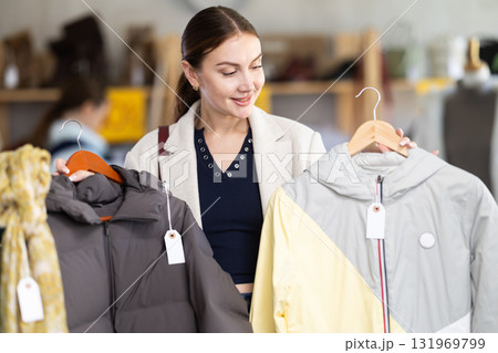 Adult woman chooses down jacket in clothing store 131969799