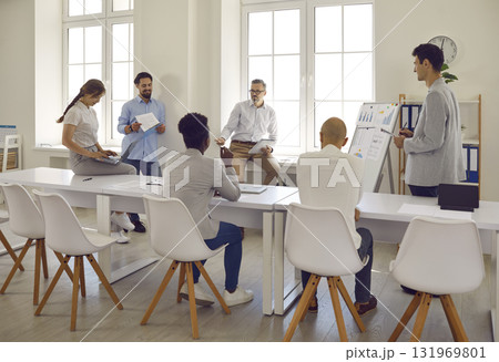 Team listens report of employee, which shows statistics of company in form of tables and graphs on whiteboard. Team listens report of employee, which shows statistics of company in form of tables and graphs on whiteboard. 131969801