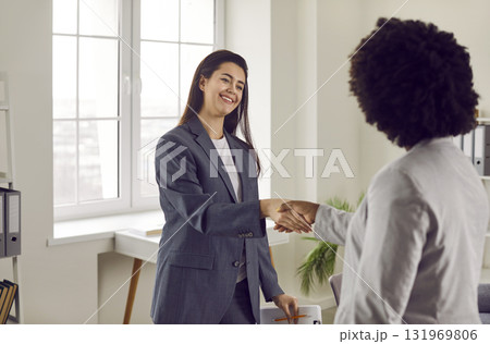 Two happy young business women meet in the office, smile and exchange handshakes 131969806
