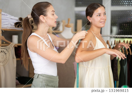 Young female dressmaker measuring woman client 131969815