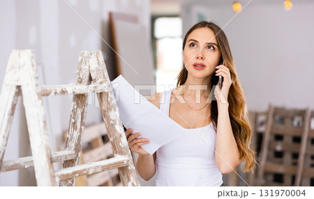Woman having telephone convesrtion in construction site 131970004