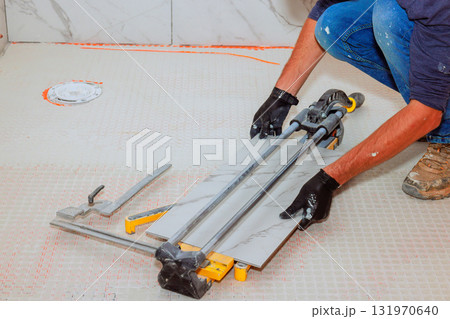 Worker on cutting large marble tile on floor in busy construction bathroom 131970640