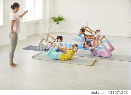 Group of flexible children doing gymnastic exercises on gym floor at sports school 131971298