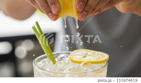 Hands squeezing fresh lemon juice into a glass of ice. Making a refreshing summer drink with lemongrass. Healthy lifestyle concept Hands squeezing fresh lemon juice into a glass of ice. Making a refreshing summer drink with lemongrass. Healthy lifestyle concept 131974619