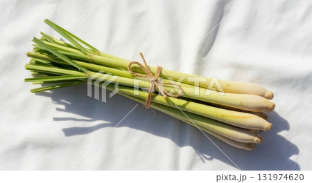 Fresh lemongrass stalks tied in a bunch on a white background. Aromatic herb and spice for Asian cuisine. Top view flat lay with natural sunlight Fresh lemongrass stalks tied in a bunch on a white background. Aromatic herb and spice for Asian cuisine. Top view flat lay with natural sunlight 131974620