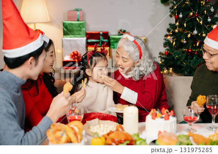 Celebrate Christmas with family in a cozy, festive setting. Santa hats, gifts, and delicious food capture the warmth, joy 131975285