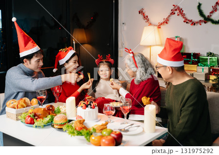 Celebrate Christmas with family in a cozy, festive setting. Santa hats, gifts, and delicious food capture the warmth, jo Celebrate Christmas with family in a cozy, festive setting. Santa hats, gifts, and delicious food capture the warmth, jo 131975292