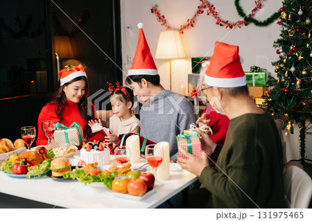 Celebrate Christmas with family in a cozy, festive setting. Santa hats, gifts, and delicious food capture the warmth, joy, Celebrate Christmas with family in a cozy, festive setting. Santa hats, gifts, and delicious food capture the warmth, joy, 131975465