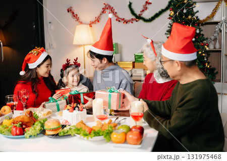Celebrate Christmas with family in a cozy, festive setting. Santa hats, gifts, and delicious food capture the warmth, joy, 131975468