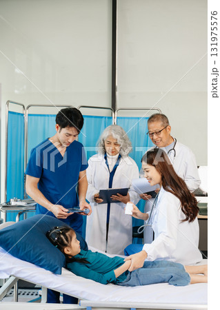 Group of Asian doctors and nurses consulting a young child patient in hospital ward. Real people, teamwork, pediatric care, diagnosis, and professional healthcare service. Group of Asian doctors and nurses consulting a young child patient in hospital ward. Real people, teamwork, pediatric care, diagnosis, and professional healthcare service. 131975576