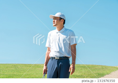 パターとゴルフクラブを持ってゴルフ場を歩く男性 パターとゴルフクラブを持ってゴルフ場を歩く男性 131976350