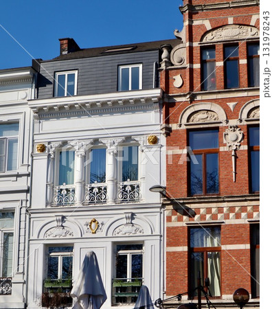 Architectural contrast: a neoclassical white stucco facade with columns next to an ornate red brick Neo-Renaissance building in Antwerp, Belgium 131978243