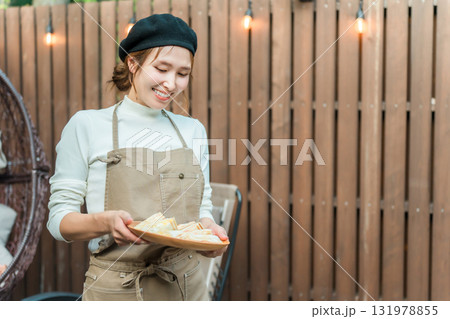 おしゃれなカフェで働くエプロン姿の若いアジア人女性 おしゃれなカフェで働くエプロン姿の若いアジア人女性 131978855