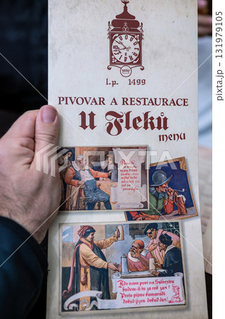 Prague, Czech Republic, August 7, 2023. A shot of the menu at U Fleku, the oldest and most famous brewery in the city. It's held up by the hand of a Caucasian man sitting at a table. Travel 131979105
