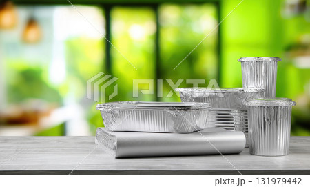 Stack of Various Empty Aluminum Foil Takeaway Containers and Rolls of Food Wrap on Wooden Table with Blurry Green Restaurant, Highlighting Concepts of Food Delivery, Catering, Eco-Friendly Packaging Stack of Various Empty Aluminum Foil Takeaway Containers and Rolls of Food Wrap on Wooden Table with Blurry Green Restaurant, Highlighting Concepts of Food Delivery, Catering, Eco-Friendly Packaging 131979442